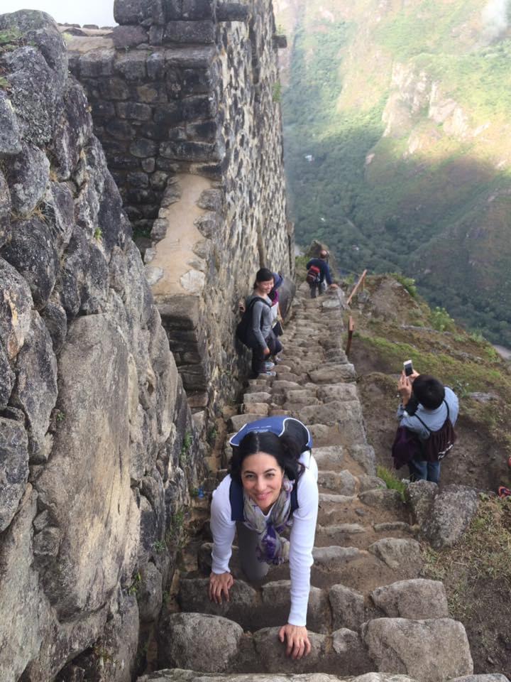People hiking narrow stone stairs on mountain trail.