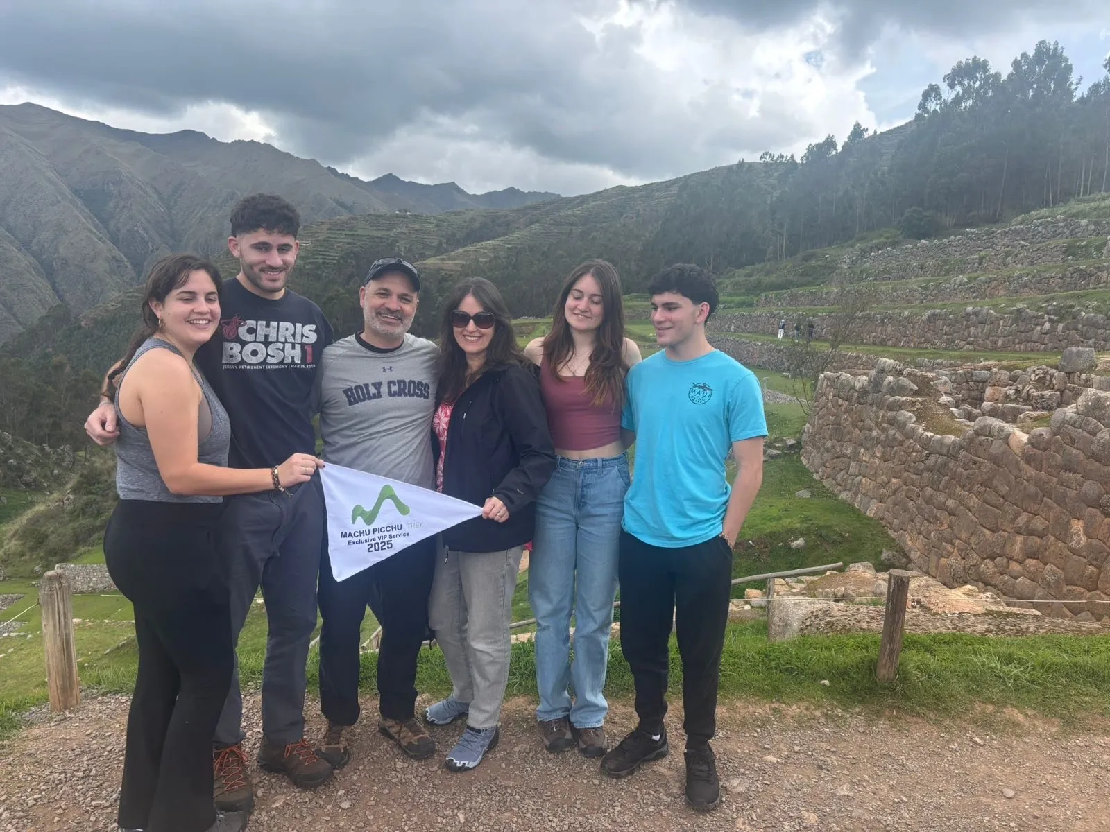 Group holding Machu Picchu trek 2025 flag, smiling