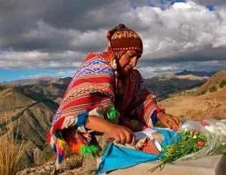 Person in traditional attire arranging flowers outdoors.